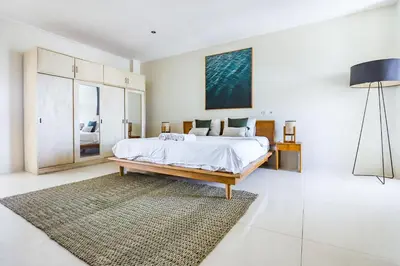a white bedroom with a bed and a rug at Canggu Art Loft - Luxury Stay with Berawa View 2BDR in Canggu