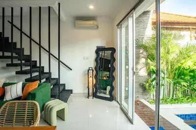 a living room with a green couch and a staircase at Central Cozy Villa 3BR 5min walk to shops, beach in Legian