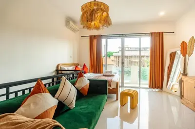 a living room with a green couch and a balcony at Central Cozy Villa 3BR 5min walk to shops, beach in Legian