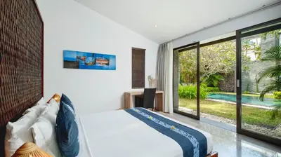 a bedroom with a bed and a view of a pool at Villa Anjali Blue by Villa Finder in Seminyak