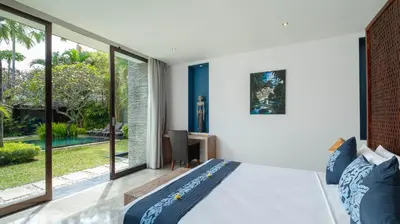 a bedroom with a large bed and large windows at Villa Anjali Blue by Villa Finder in Seminyak