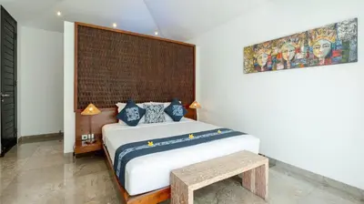 a bedroom with a large bed with a wooden headboard at Villa Anjali Blue by Villa Finder in Seminyak