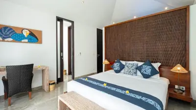 a bedroom with a large bed with blue and white pillows at Villa Anjali Blue by Villa Finder in Seminyak