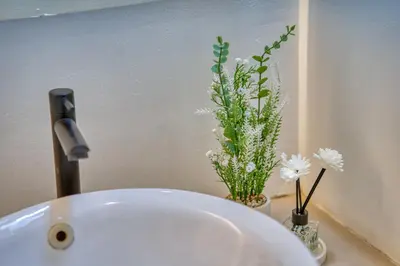 a white sink with two vases with flowers on it at 3 Bed Cozy Mediterranean-Style Escape in Berawa in Canggu