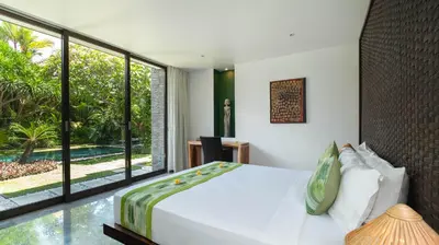 a bedroom with a white bed and a large window at Villa Anjali Green by Villa Finder in Seminyak