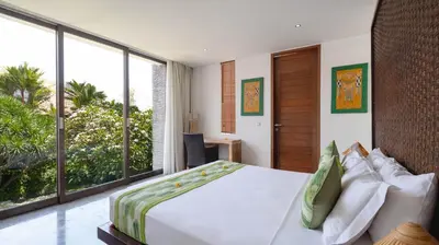 a bedroom with a large bed and large windows at Villa Anjali Green by Villa Finder in Seminyak