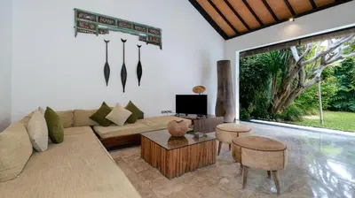 a living room with a couch and a tv at Villa Anjali Green by Villa Finder in Seminyak