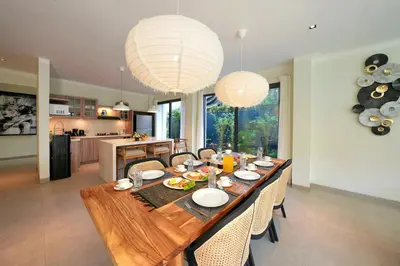 a dining room table with chairs and two chandeliers at Twin Villas Cora & Zeno by Exotic Bali Properties in Seminyak