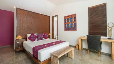 a bedroom with a bed and a desk and a table at Villa Anjali Purple by Villa Finder in Seminyak
