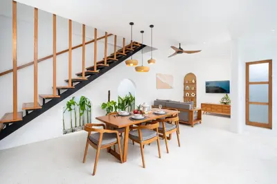 a dining room with a table and chairs and a staircase at Villa Mandara Double Six in Legian