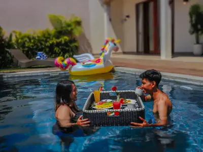 a man and woman in a swimming pool with a tray of food at Villa Sinergi Seminyak 4 in Seminyak