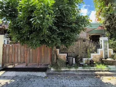 a wooden fence with a tree in front of a house at Villa Yoni in Bali in Pesanggaran