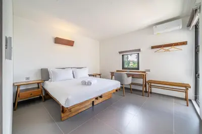a white bedroom with a bed and a desk at Casa Nadi in Seminyak