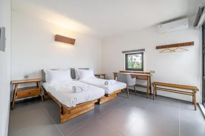 a bedroom with two beds and a desk and a window at Casa Nadi in Seminyak