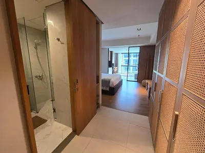 a bathroom with a walk in shower and a bedroom at de' Asasta Apartment Benoa N-511 in Nusa Dua