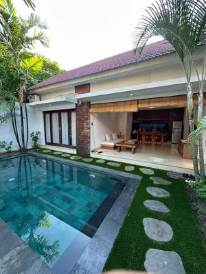 a villa with a swimming pool in front of a house at Villa Lil'u in Seminyak