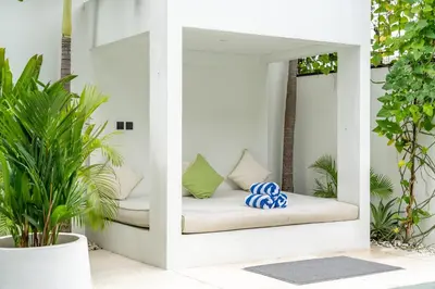 a white porch with a bed in a room with plants at Villa Vantage 8, Umalas in Kerobokan