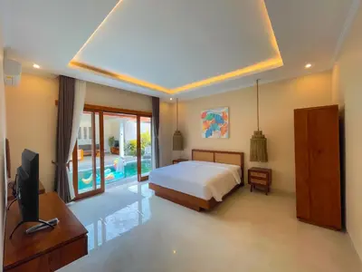 a bedroom with a bed and a television and a pool at Villa Sinergi Seminyak 3 in Seminyak