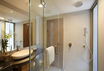a bathroom with a glass shower and a sink at d'primahotel Petitenget Seminyak 2 in Seminyak