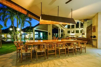 a dining room with a large wooden table and chairs at Abaca Villas in Seminyak