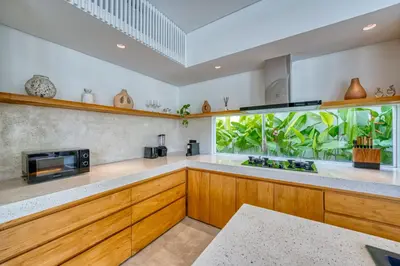 a kitchen with wooden cabinets and a large window at Luxury Industrial-Style 2BR Villa Kirma Near the Beach in Canggu