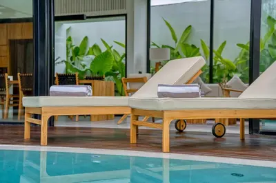 two beds sitting next to a swimming pool at Luxury Industrial-Style 2BR Villa Kirma Near the Beach in Canggu