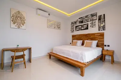 a white bedroom with a bed and a table at Danbi Villa Bali By Bali Cabin in Canggu