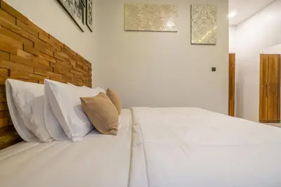 a white bed with white pillows and a brick wall at Danbi Villa Bali By Bali Cabin in Canggu