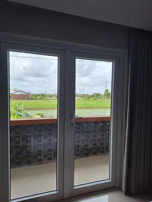 two windows in a room with a view of a field at Home88 Sanur in Sanur
