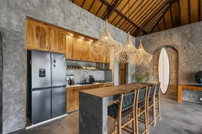 a kitchen with stainless steel refrigerator and wooden cabinets at Brand New 4BR Villa with Pool, Sauna & Fire pit close to Nusa Dua and Uluwatu in Jimbaran