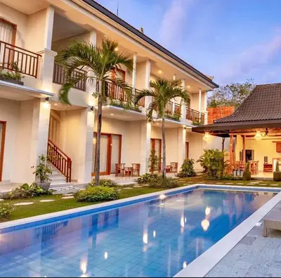 a swimming pool in front of a house at Sari alam guest house in Kerobokan