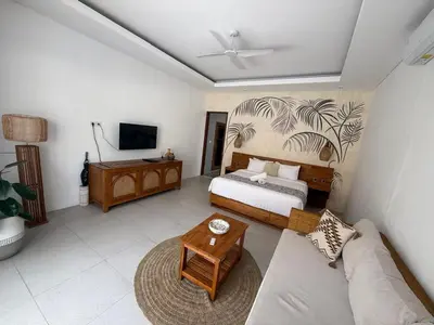 a bedroom with a bed and a couch and a tv at Santai Suites Nusa Dua-Child Free in Nusa Dua