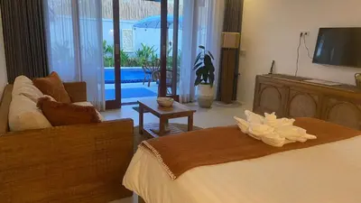 a bedroom with a bed and a couch and a television at Santai Suites Nusa Dua-Child Free in Nusa Dua