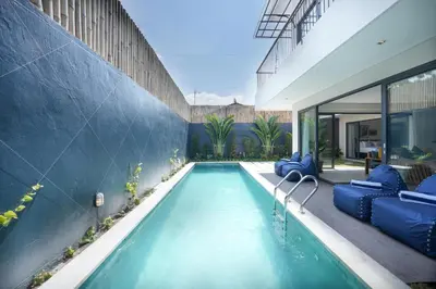a swimming pool with blue chairs and a house at Twin Villas Drupadi 8BR Seminyak by Exotic Bali Properties in Seminyak