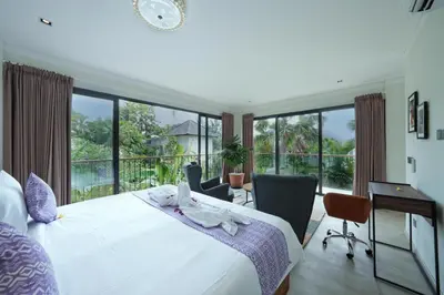a bedroom with a bed and a desk and windows at Twin Villas Drupadi 8BR Seminyak by Exotic Bali Properties in Seminyak