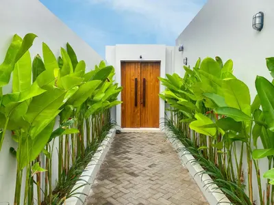 a hallway with plants and a wooden door at The Aurum Canggu Villas by Nagisa Bali in Canggu