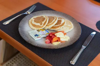 a plate with pancakes and fruit on a table at The Aurum Canggu Villas by Nagisa Bali in Canggu