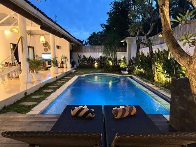 a swimming pool with two chairs next to a house at A strategic 2 bedroom villa in seminyak in Seminyak
