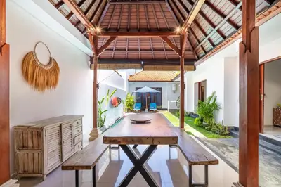 an indoor dining room with a wooden table and benches at Villa Azure 3 - Tropical 4-Bedroom Pool Villa Near Seminyak in Seminyak