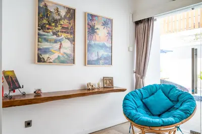a room with a blue chair and paintings on the wall at Villa Azure 2 - Master Suite in shared Pool Villa in Seminyak