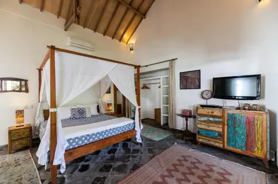 a bedroom with a canopy bed and a flat screen tv at Villa Damai Manis in Seminyak