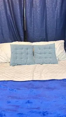 two pillows on a bed with blue and white sheets at Santorini House in Bali Near Airport in Kuta