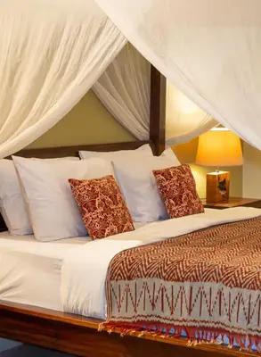 a bedroom with a bed with white sheets and pillows at The Clovewood Villa in Seminyak