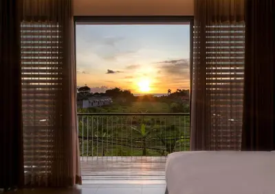 a bedroom with a view of the sunset through a window at Swan Villa R in Seminyak