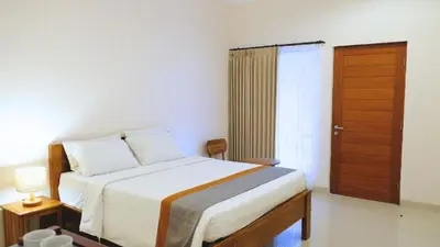 a bedroom with a bed and a wooden door at Deva Guest House - Kerobokan in Seminyak