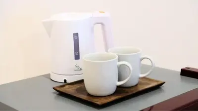 two white cups on a wooden tray next to a blender at Deva Guest House - Kerobokan in Seminyak