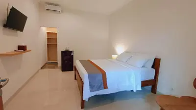 a bedroom with a white bed and a tv at Deva Guest House - Kerobokan in Seminyak