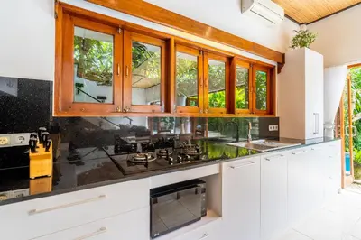 a kitchen with white cabinets and black counter tops at Tropical Villas - 2 Bed & 3 Bed in Kerobokan