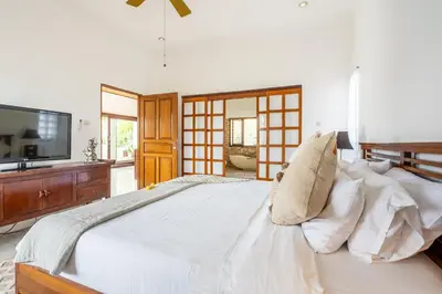 a bedroom with a large white bed and a tv at Tropical Villas - 2 Bed & 3 Bed in Kerobokan