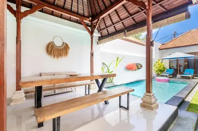 an outdoor dining area with benches and a swimming pool at Villa Azure 3 - Private Suite in Shared Tropical Pool Villa in Seminyak